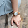 WILD CLOUD ZW10 – Women's olive wood watch worn on the wrist near a bench